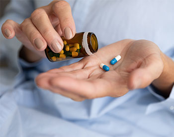 Elderly sick ill woman hold two pills on hand pouring capsules from medication bottle take painkiller supplement medicine